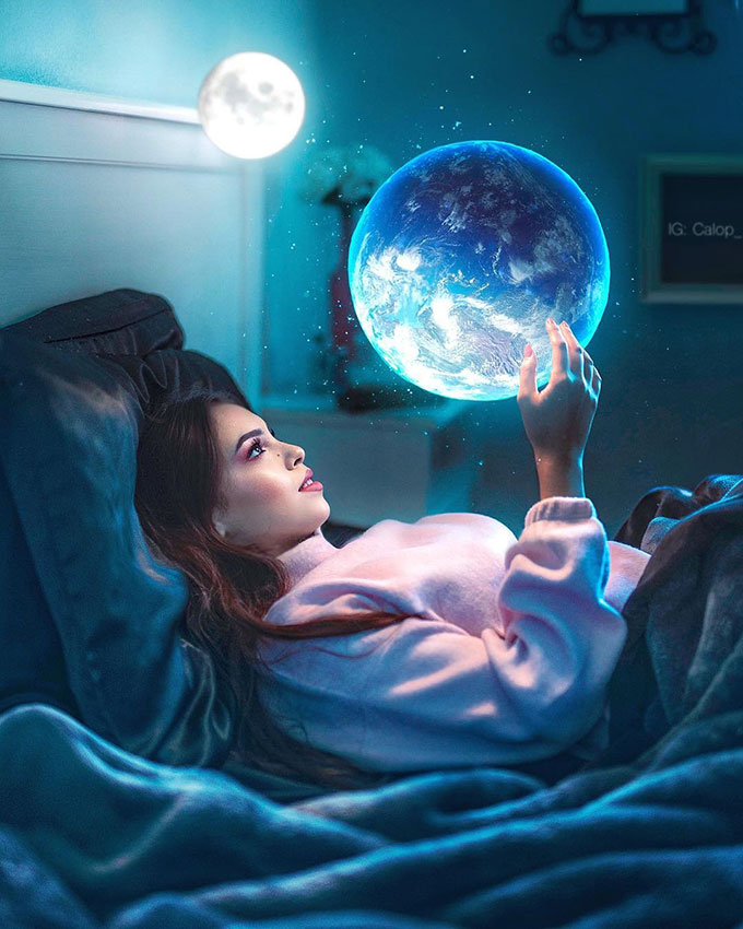 Girl lying on bed staring at floating small glowing earth