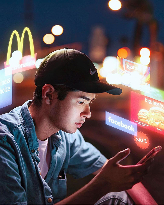 Man on his phone with glowing ads around him